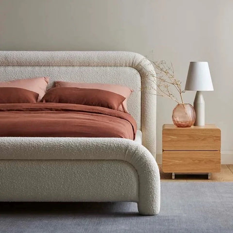 Alexis curved bed in ivory boucle upholstery, styled in a bedroom setting