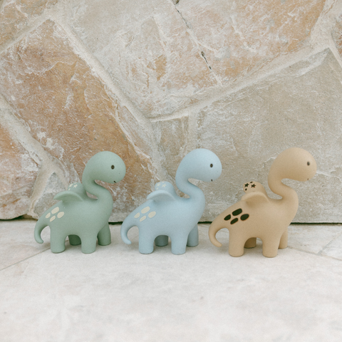 Baby holding Diplo the Dino-Dragon teether by winding neck