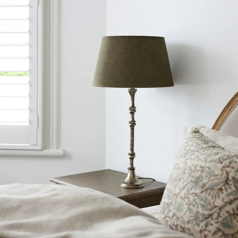 Table lamp on a nightstand next to a bed with pillows