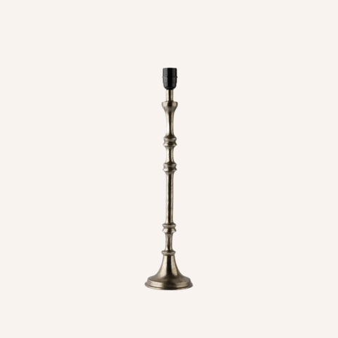 A single tall candlestick-style table lamp with an antique bronze metal base