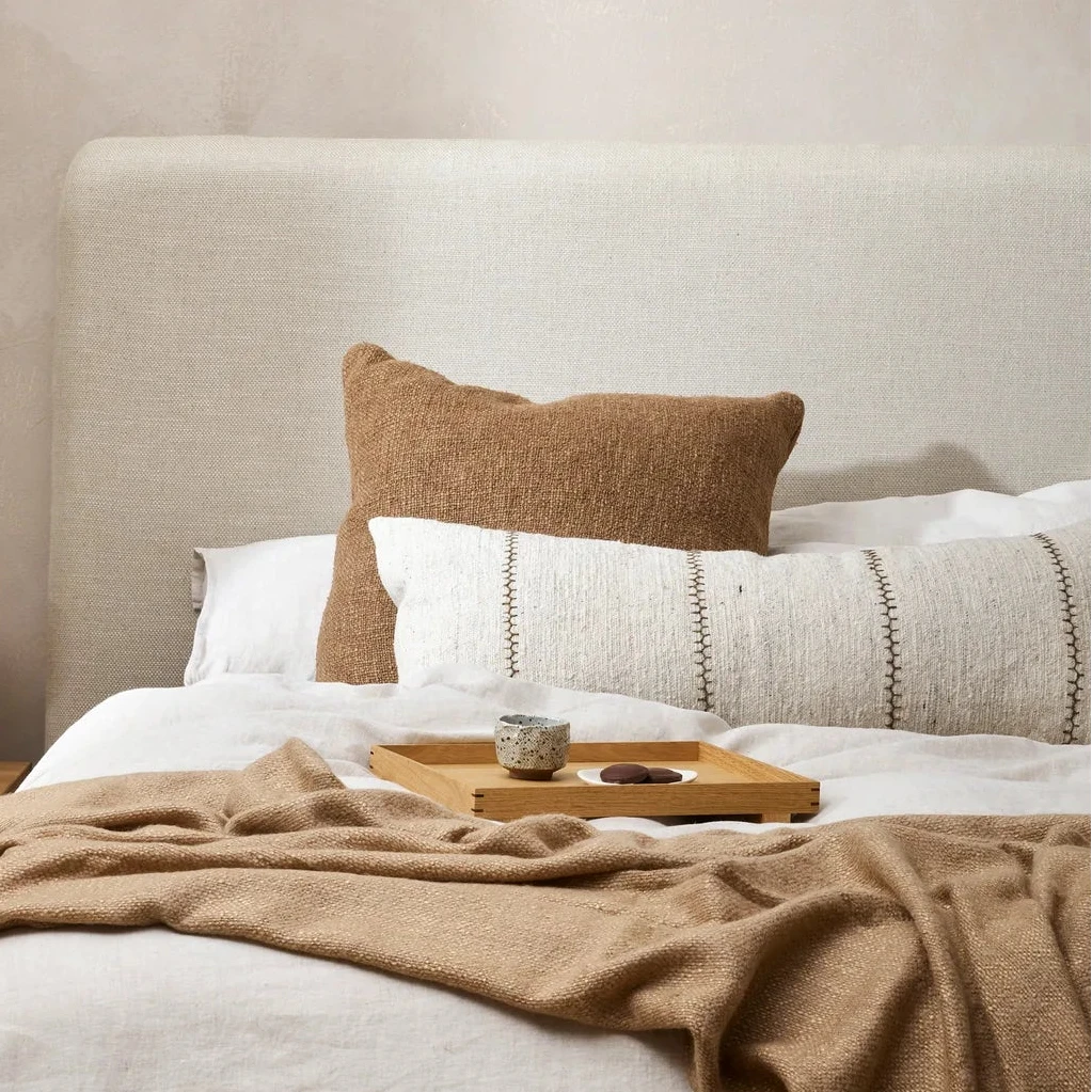 Cyprus Cocoa cushion styled with linen throws on a bed