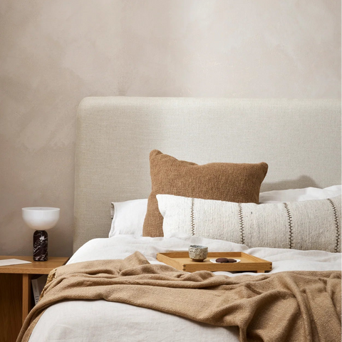 Cyprus Cocoa cushion styled with linen throws on a bed