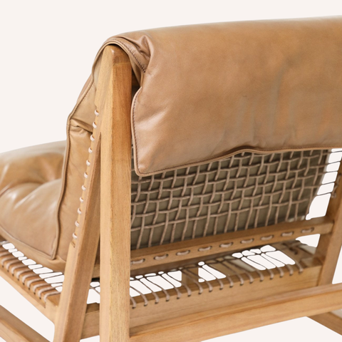 Close-up of a wooden lounge chair with tan leather cushions and a woven seat and backrest, shown against a plain light background.