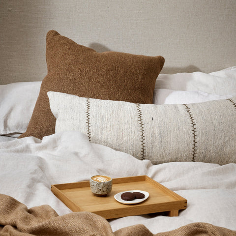Handwoven cocoa-toned cotton linen cushion, 60x60cm, styled on a bed
