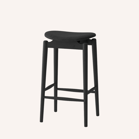 A modern black bar stool with a curved upholstered seat and four tapered legs, shown against a solid off-white background.