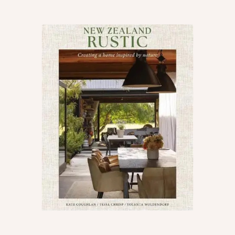 Book cover for 'New Zealand Rustic: Creating a home inspired by nature' by Kate Coughlan, Tessa Creep, and Yolanda Woldendorp, featuring a rustic outdoor patio dining scene with beige chairs, dark pendant lights, and greenery.