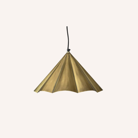 A modern pendant light with a pleated, umbrella-like shade in a warm brass or gold finish, suspended by a thin black cord against a solid off-white background.