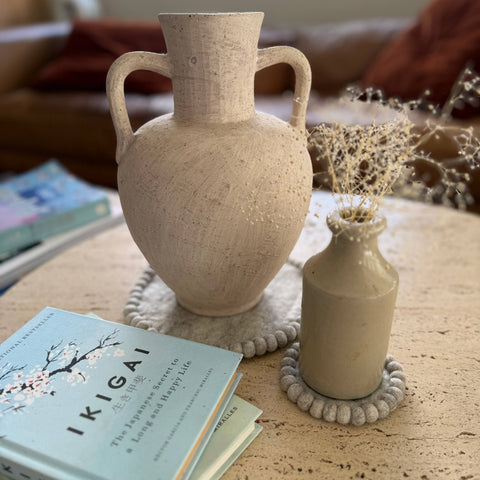 Set of four felt coasters styled with ceramic vases and book