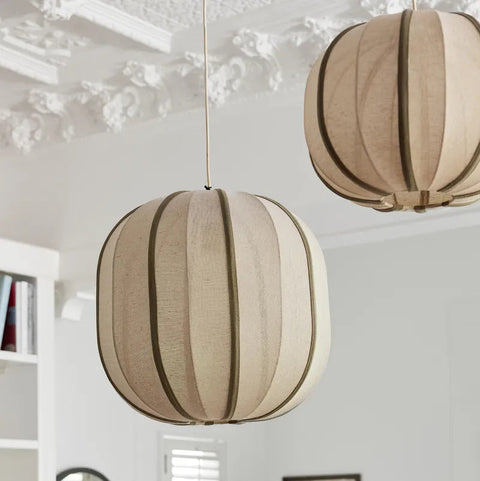 Two beige spherical pendant lights hanging in a room with decorative elements.