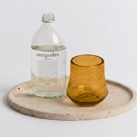 Tom Tumbler amber mouth-blown spot pattern drinking glass on a stone tray