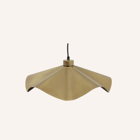 A modern pendant light with a wavy, scalloped metal shade in a brushed brass or gold finish, suspended by a black cord against a solid off-white background.