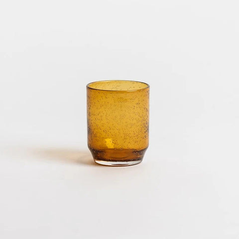 an amber glass tumbler centered on a light gray background.
