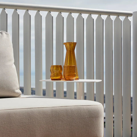 Beige outdoor sofa with a small table and decorative items on a balcony.
