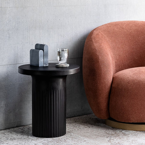 black concrete side table styled beside a sofa in a contemporary living room