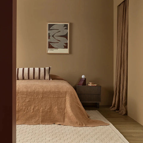 cushion styled at the head of a bed with neutral linens