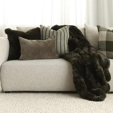 Pelage Throw in Olive faux fur styled draped over a sofa