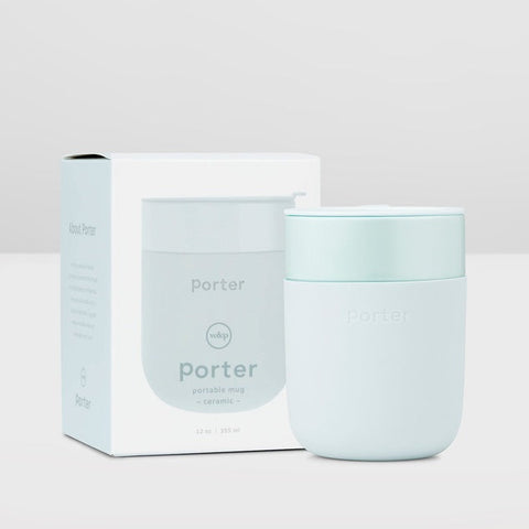 A light pastel mint portable mug by Porter next to its white and pale blue packaging box, set against a clean, light gray studio background.